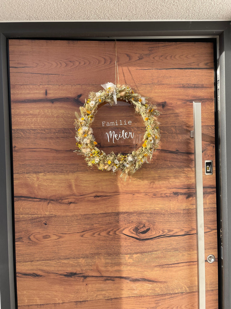 Trockenblumenkranz mit einer "Familie Meiler" personalisierten Acrylglasscheibe, Trockenblumenkranz hängt an einer Tür