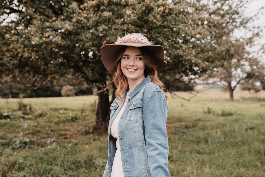 Frau; Jeansjacke mit Herz; Jeansjacke mit Herz-Bestickung; Natur; Hut; Kleid; Jeansjacke; Lächelnde Frau, Trockenblumen Hut