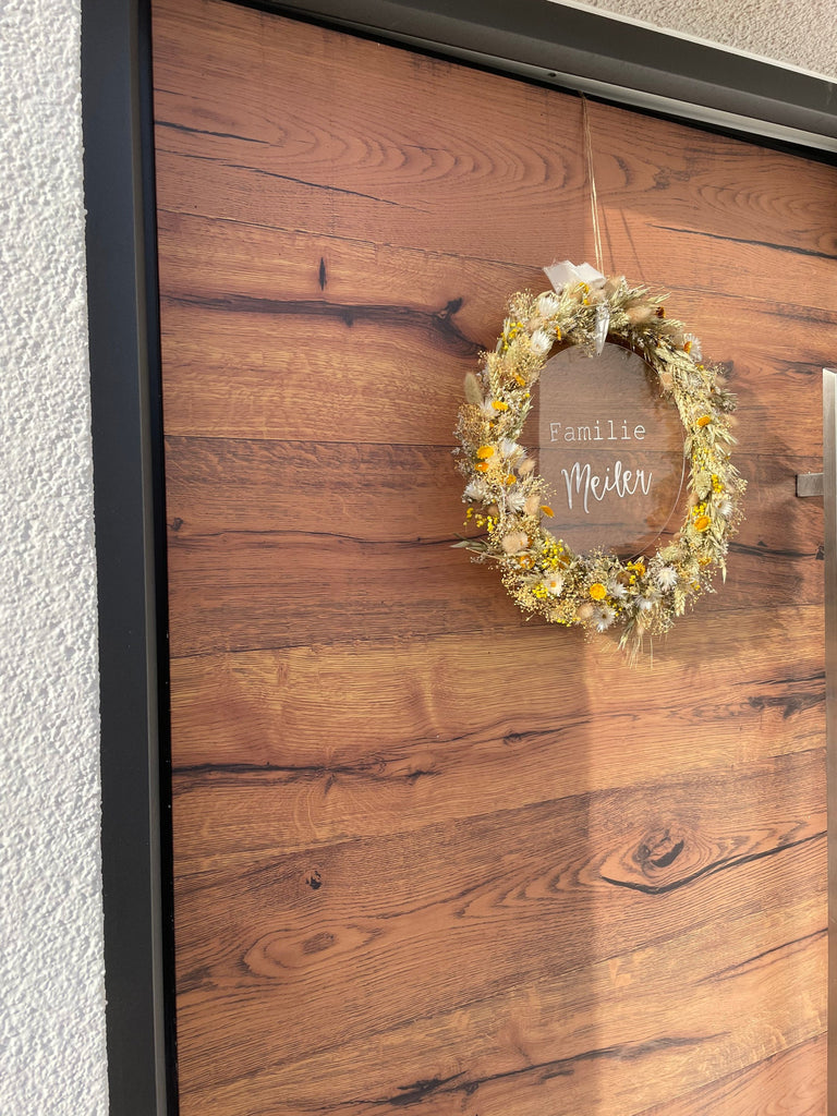 Trockenblumenkranz mit einer "Familie Meiler" personalisierten Acrylglasscheibe, Trockenblumenkranz hängt an einer Tür