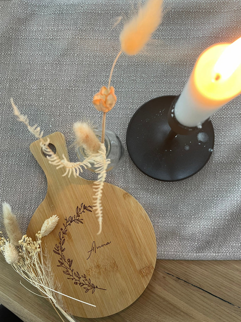 Holzbrett mit Gravur neben einer Kerze