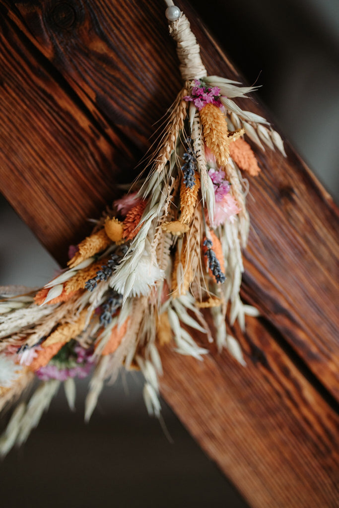 Nahaufnahme Trockenblumenkranz, Trockenblumenkranz hängt an einem Holzbalken