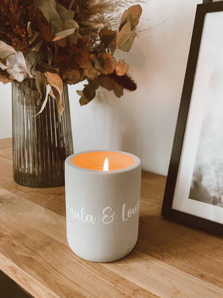 Vase mit Trockenblumen steht auf einem Holzregal, Personalisierte Kerze auf einem Holzregal, Bild mit Bilderrahmen auf einem Holzregal 