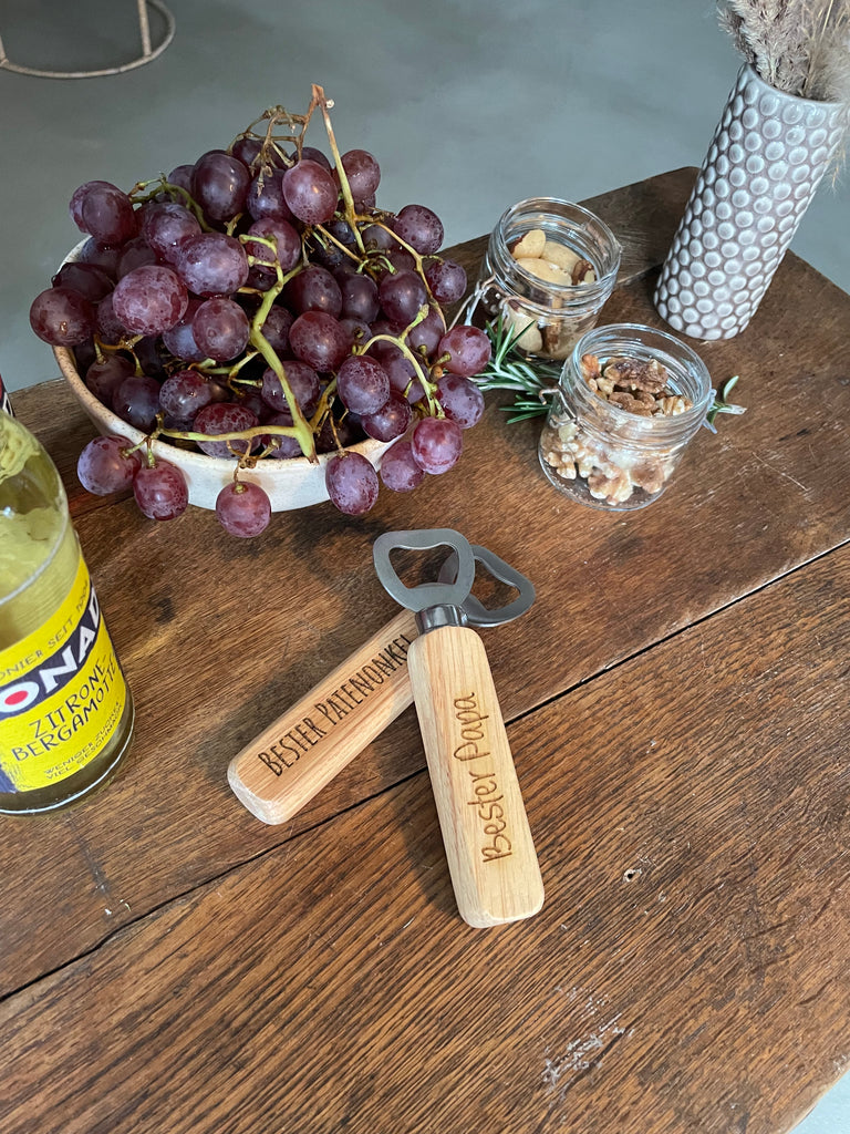 Weintrauben, Bionade, Holz Flaschenöffner mit Gravur, Glasbehälter, Vase mit Trockenblumen, Holztisch, Stuhlbein